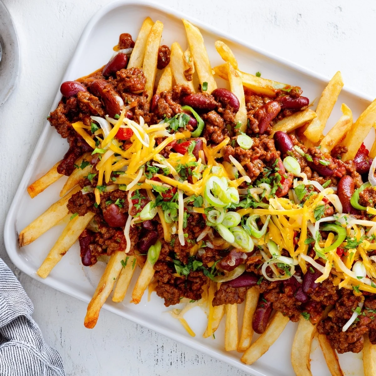 Crispy golden fries loaded with savory beef chili and melted cheddar cheese, served hot on a platter.
