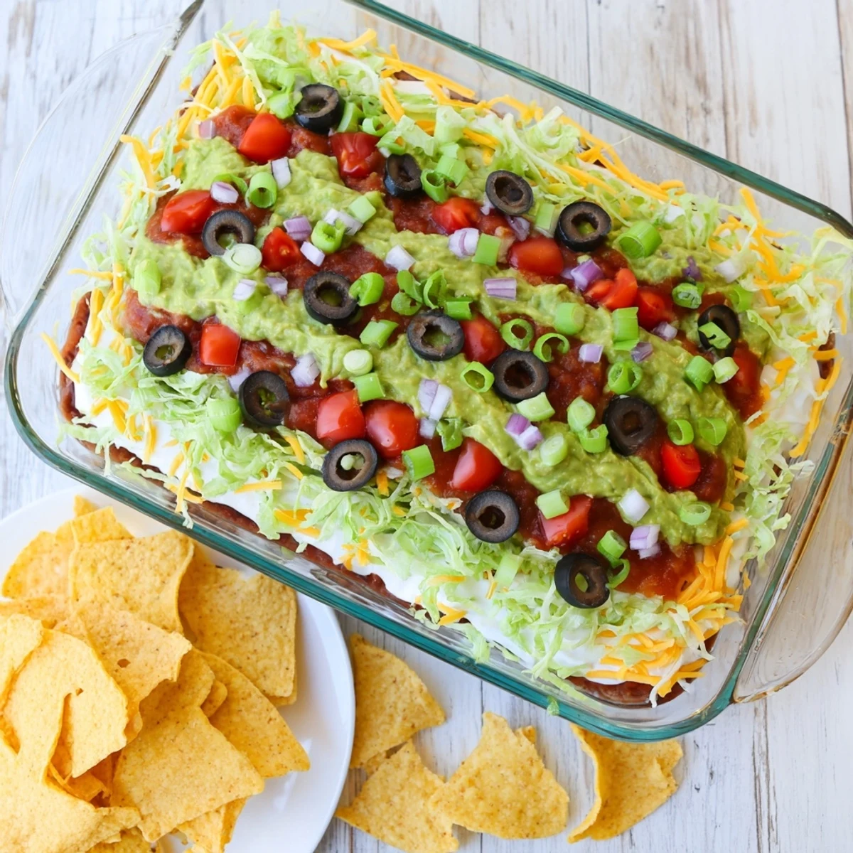 Freshly made Seven-Layer Dip with colorful toppings like olives, lettuce, and green onions.