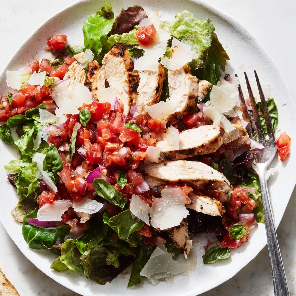 Bright red tomatoes and basil mingle with tender grilled chicken over crisp greens, finished with a tangy balsamic drizzle on this easy Bruschetta Chicken Salad.  