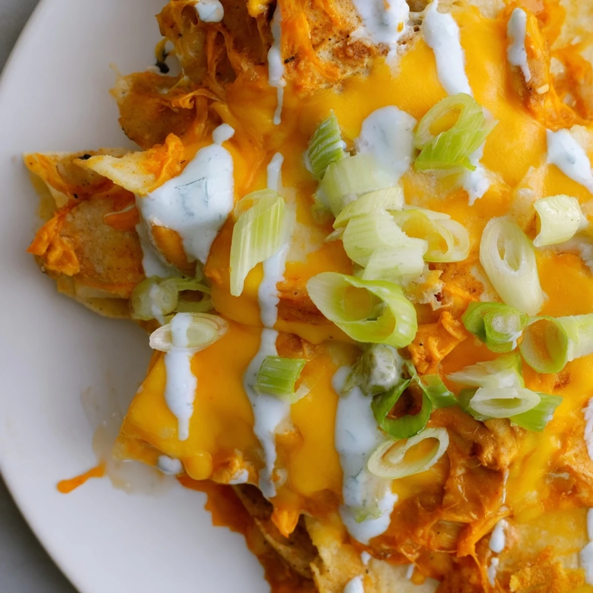 Freshly baked Buffalo Chicken Nachos topped with green onions and celery on a serving platter.  