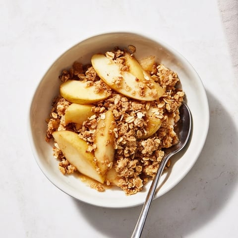 Golden brown Apple Crumble fresh from the oven, served warm in a baking dish with a scoop of vanilla ice cream melting on top.
