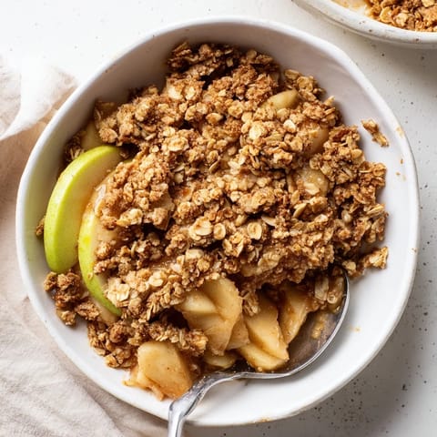 Spoonful of homemade Apple Crumble revealing layers of tender, spiced apples and a crunchy, buttery oat topping, perfect for cozy dessert lovers.