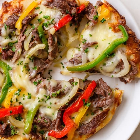 Sliced Philly Cheesesteak Pizza on a rustic board, showcasing juicy ribeye, sautéed vegetables, and a golden-brown crust.