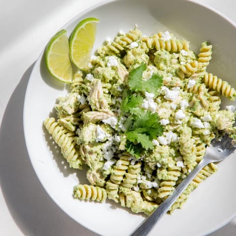 Fresh cilantro lime chicken pasta served with crumbled cotija cheese and lime wedges on the side.  