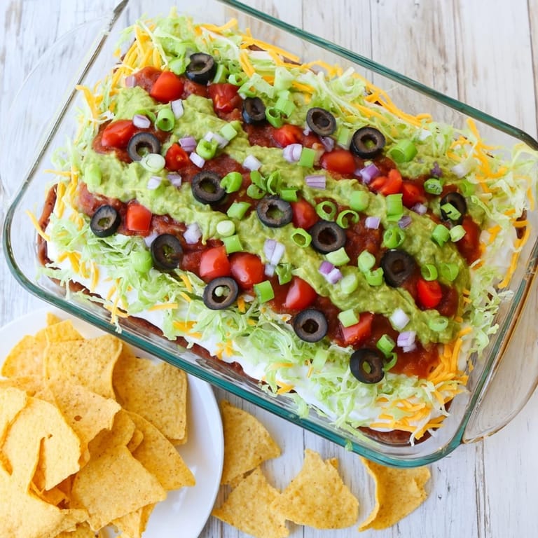 Freshly made Seven-Layer Dip with colorful toppings like olives, lettuce, and green onions.