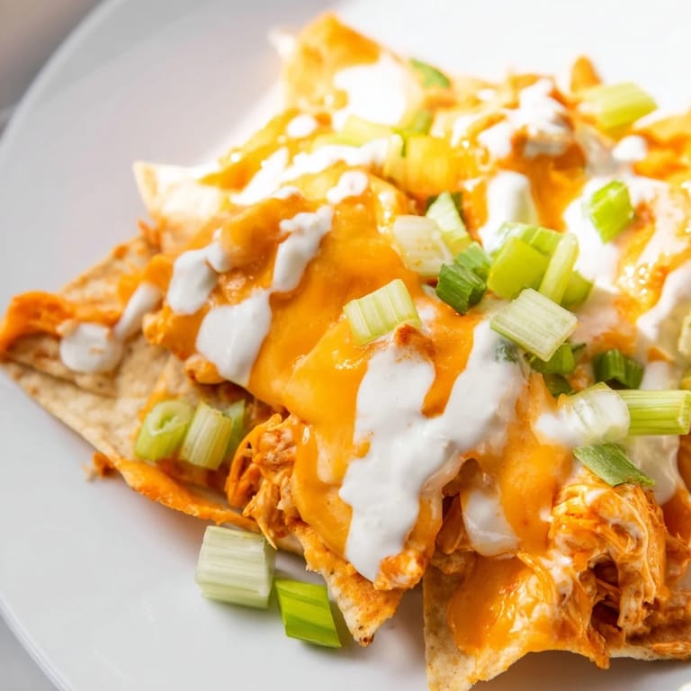 Golden, bubbly nachos drizzled with cool ranch dressing, perfect for game day snacking.