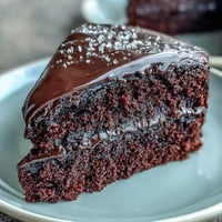 Perfectly layered Easy Chocolate Fudge Cake with silky-smooth ganache, ideal for a festive celebration centerpiece on the table.
