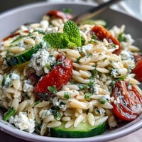 A vibrant Mediterranean orzo salad with cucumber, feta, and lemon dressing, bursting with fresh herbs and juicy tomatoes.  